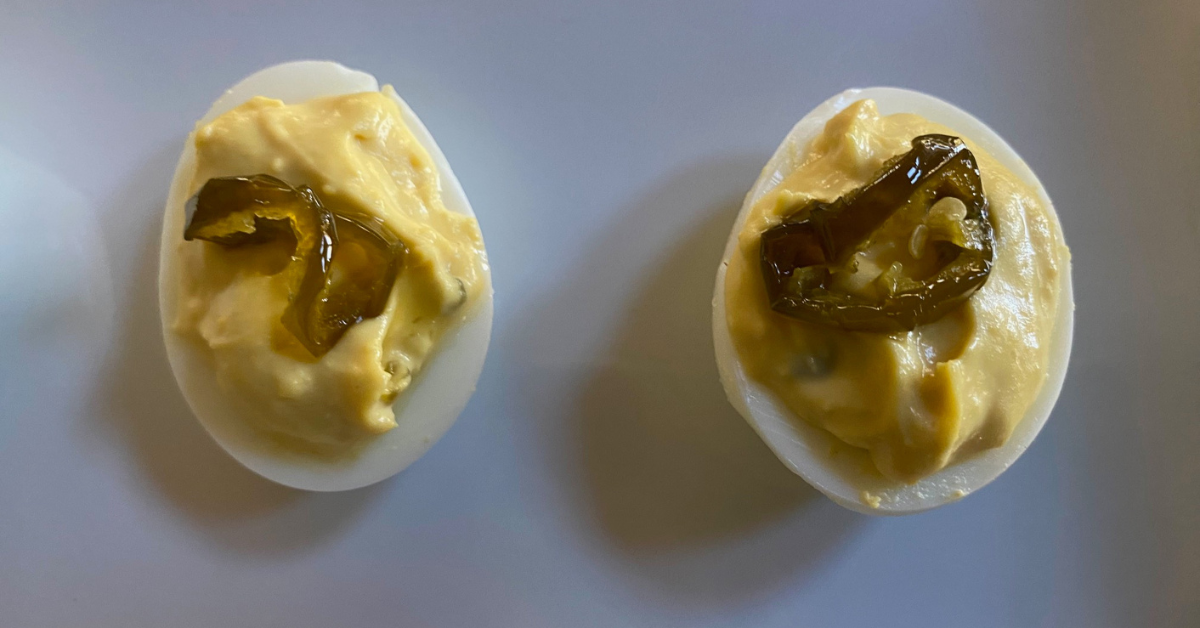 Garnish each Hot and Sweet Jalapeño Deviled Egg with a slice of hot and sweet jalapeño for flavor and presentation.