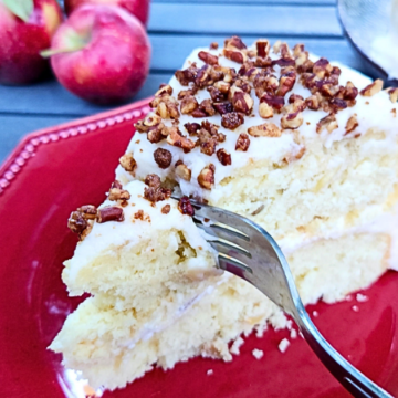 Light and fluffy vanilla cake with plump apples, topped with buttercream and candied nuts