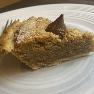 A thick layer of peanut butter cookie nestled inside a flaky pie crust and topped with milk chocolate kisses