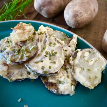 Fresh potatoes and onions are simmered in the slow cooker before they're topped with three types of cheeses and fresh chives to create slow cooker swiss chive scalloped potatoes.