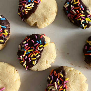 Soft and buttery, dipped in dark chocolate and topped with rainbow sprinkles, Chocolate Dipped Sprinkle Butter Cookies are melt-in your mouth delicious!