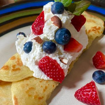 Almond berry breakfast crepes are flavored with a hint of almond and topped with homemade almond whip and fresh Summer berries.